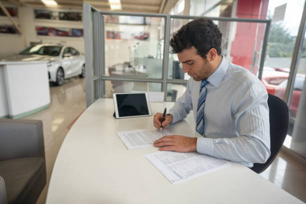 Car buyer reviewing a finance worksheet with a dealer at a desk